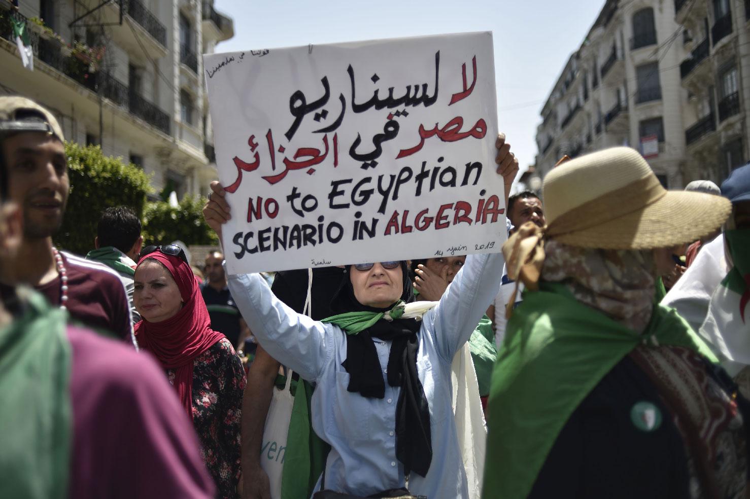 An Algerian woman raises a placard as she takes part in a weekly demonstration in the capital Algiers