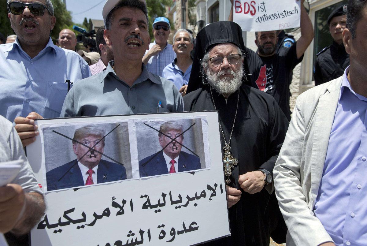 Palestinians protest in Ramallah with sign that reads, 'American imperialism is the people's enemy'.