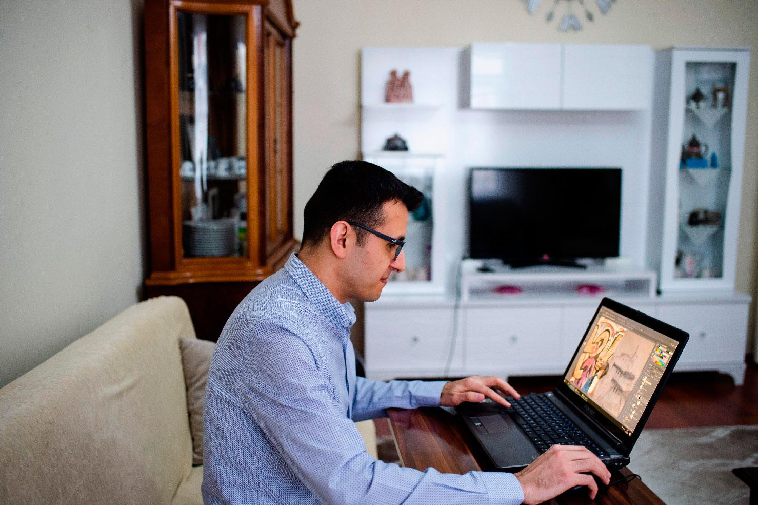 Turkish artist Ugur Gallenkus works with his laptop at his home on April 14, 2019 in Istanbul
