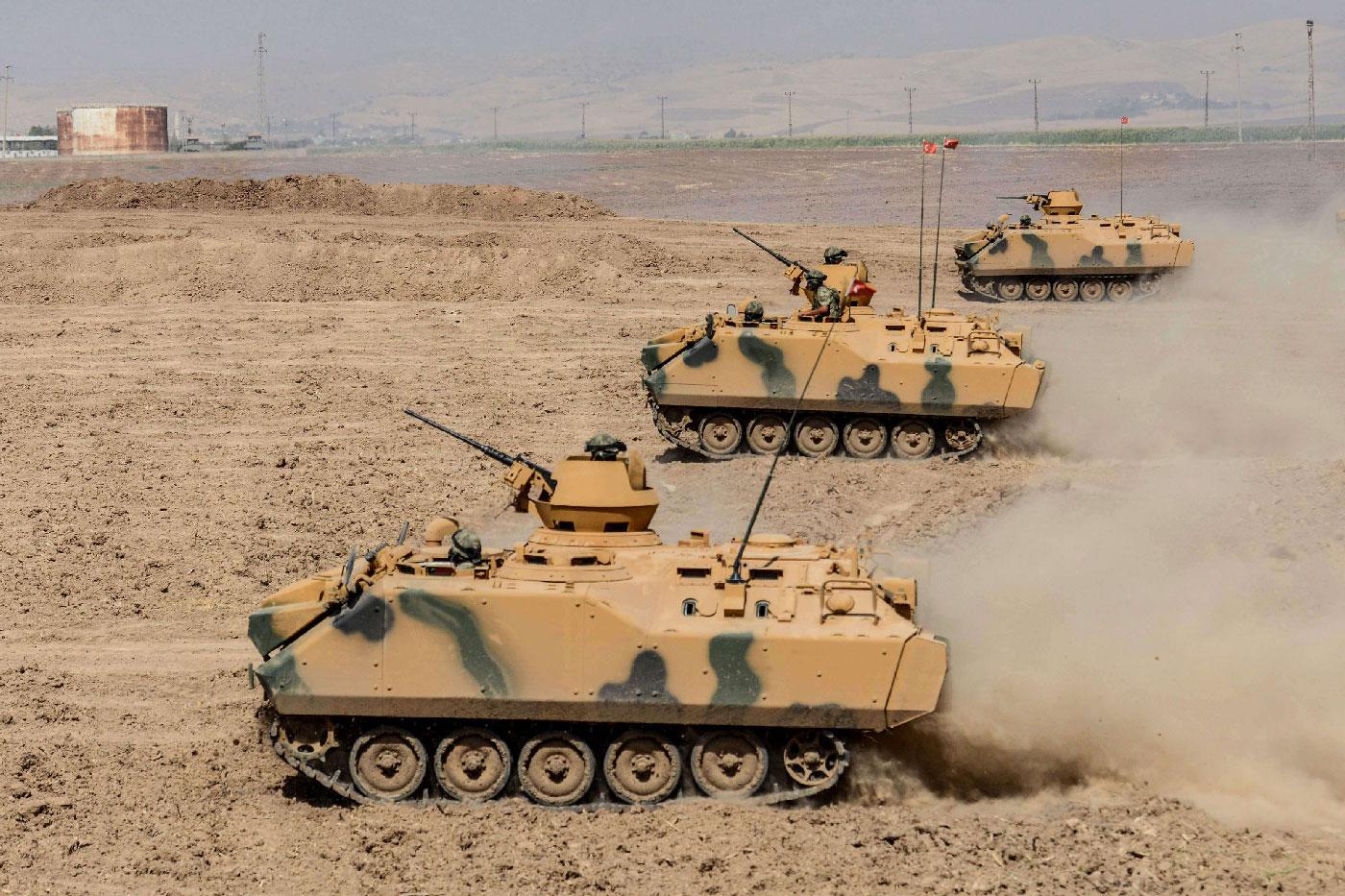 Turkish soldier ride armoured vehicles near the Habur crossing gate between Turkey and Iraq
