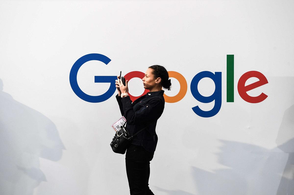 امرأة تلتقط صورة ذاتية بهاتفين أمام شعار غوغل خلال معرض للالكترونيات في باريس