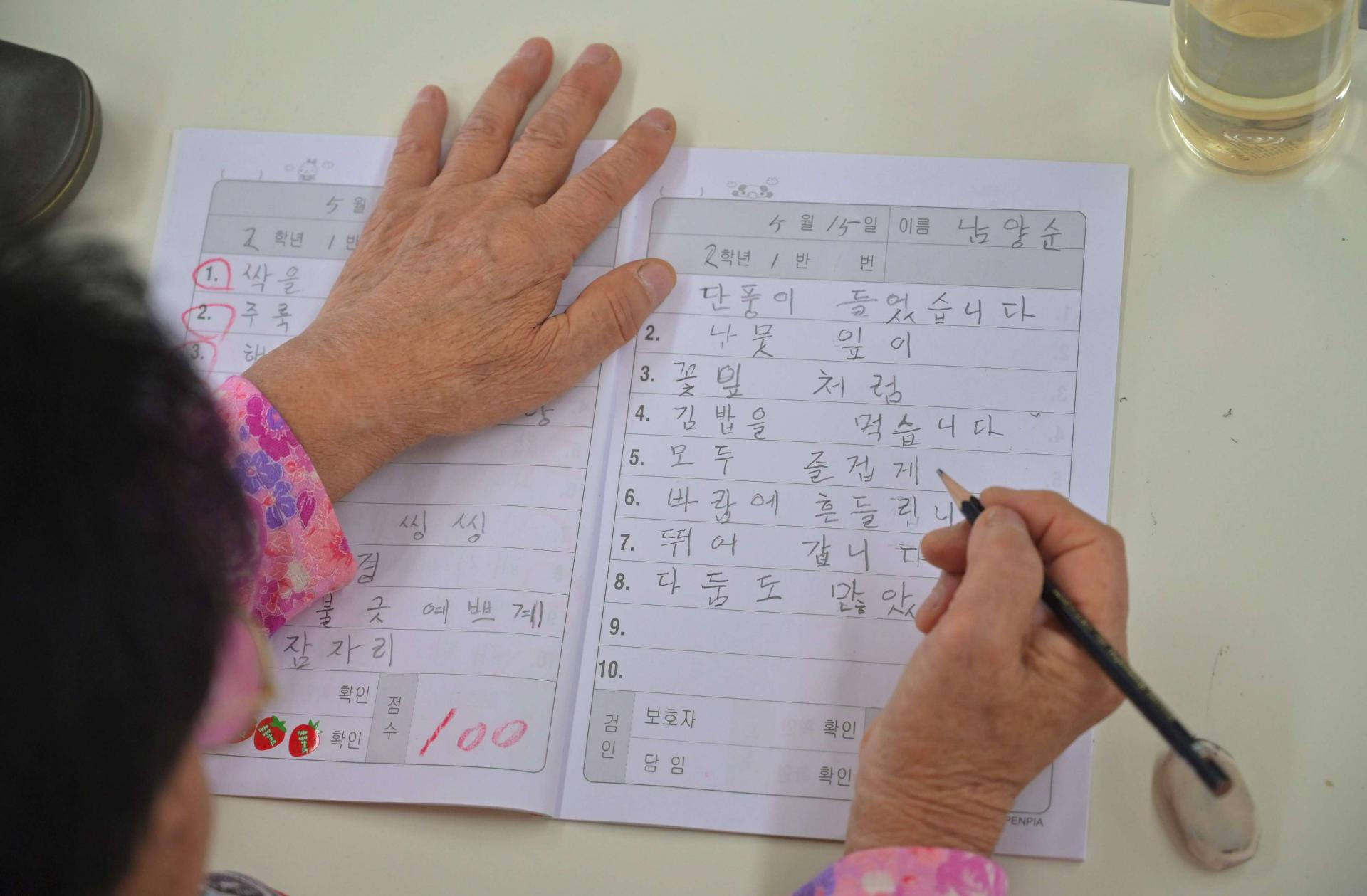امرأة مسنة من كوريا الجنوبية تجري اختبارا إملائيا في إحدى المدارس