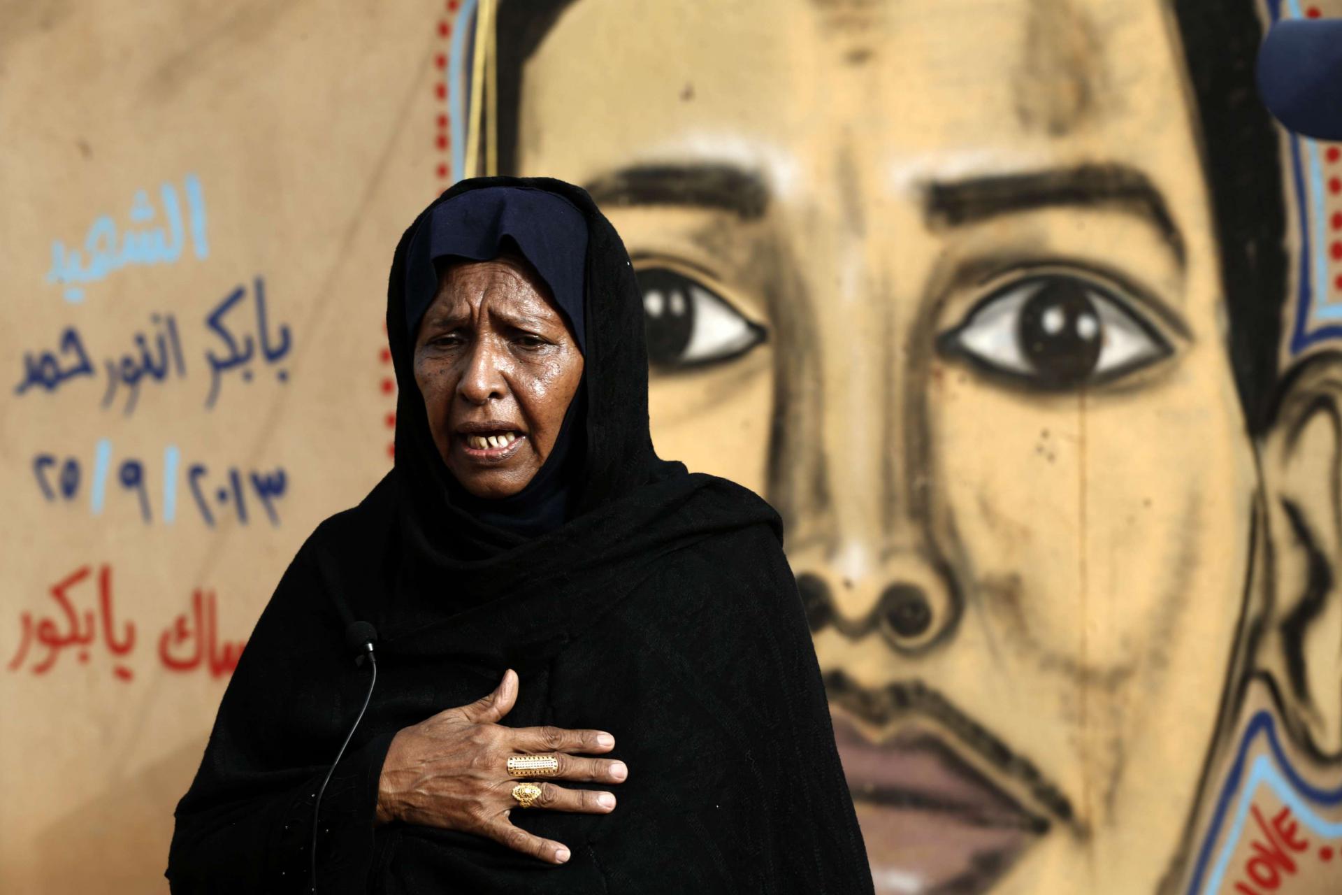 عدوية محمد والدة الشهيد بابكر أنور تقف أمام رسم يمثل ابنها على جدار في الخرطوم