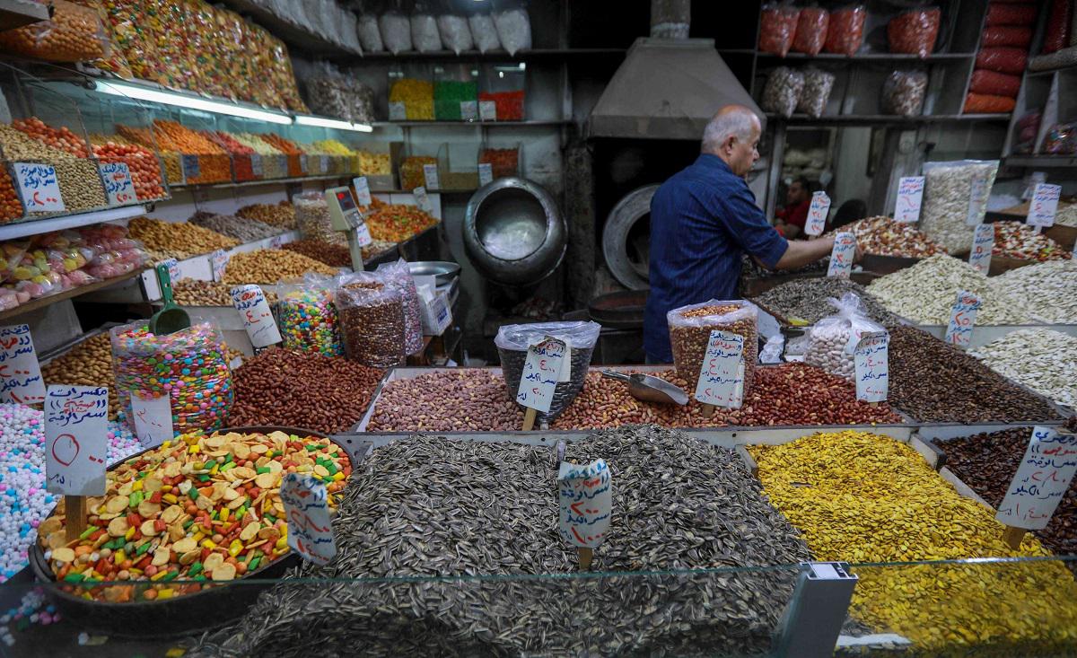 بائع سوري يعرض مجموعة متنوعة من المكسرات في متجره في دمشق