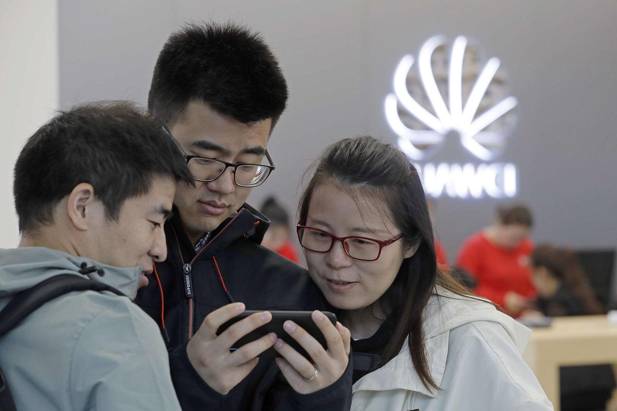 زبائن صينيون يطالعون هاتفا من هواوي في أحد متاجر الشركة في مقاطعة غوانغدونغ