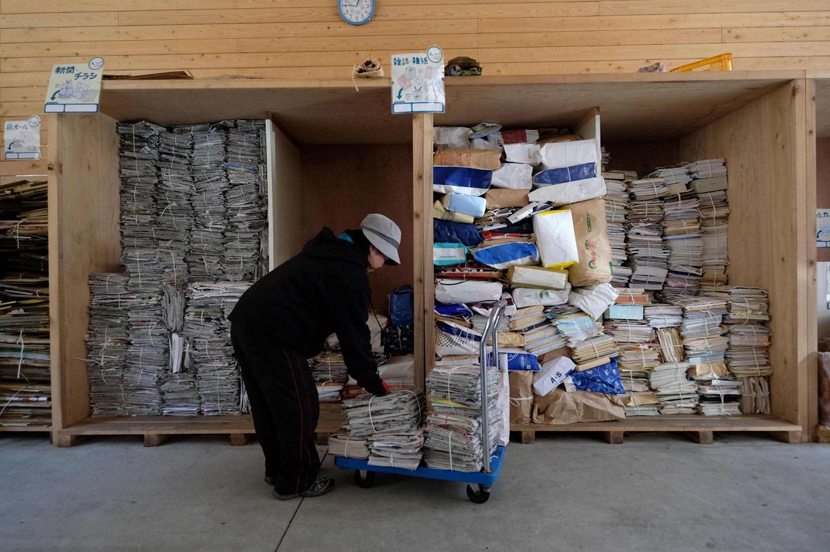 عاملة تفرز الصحف والمجلات لإعادة التدوير في مركز نفايات بلدة كاميكاتسو في اليابان