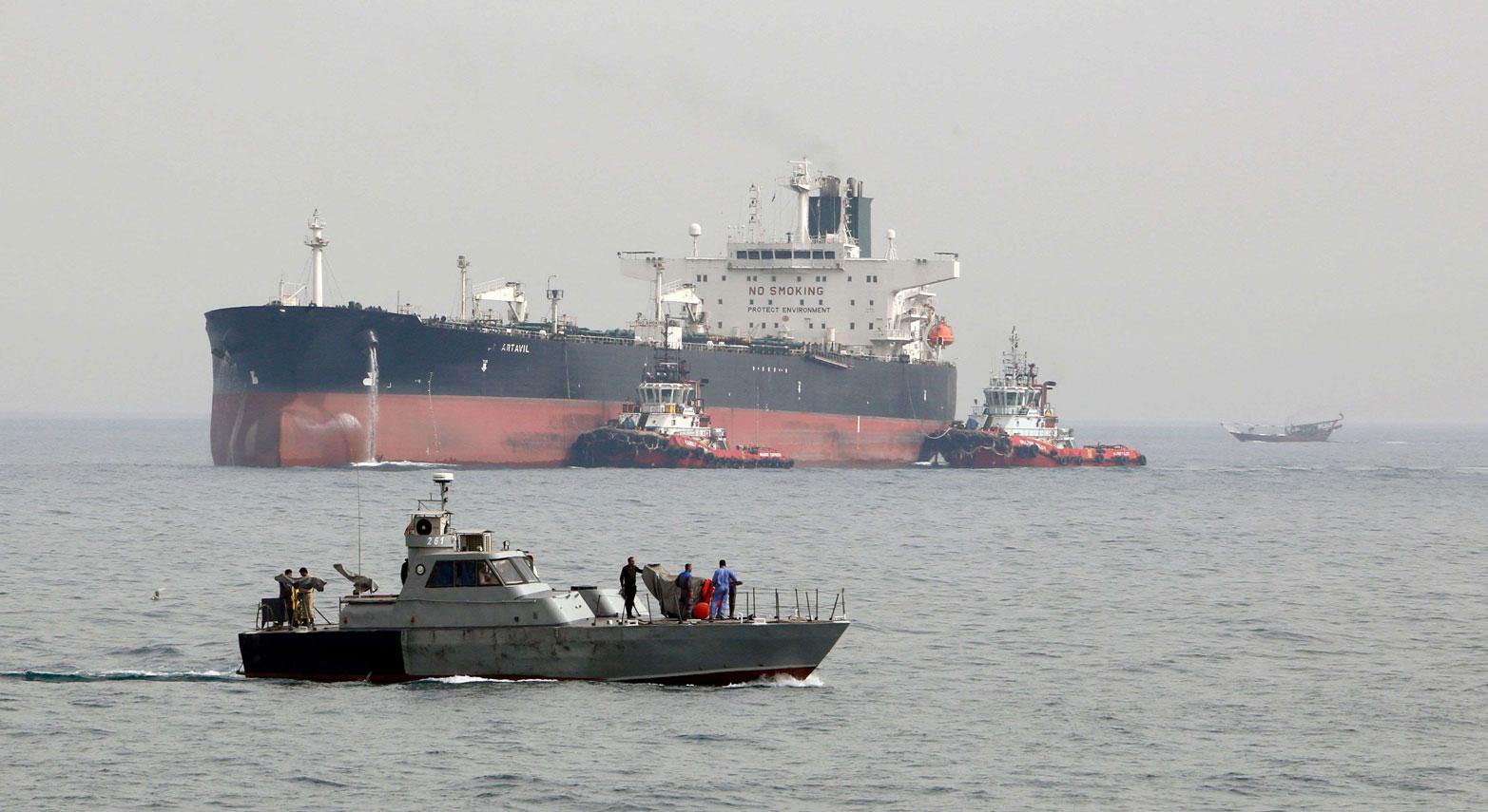 Iranian military speedboat patrols the waters as a tanker prepares to dock