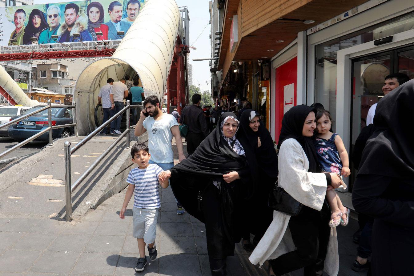 People walk in a busy street in the Iranian capital Tehran