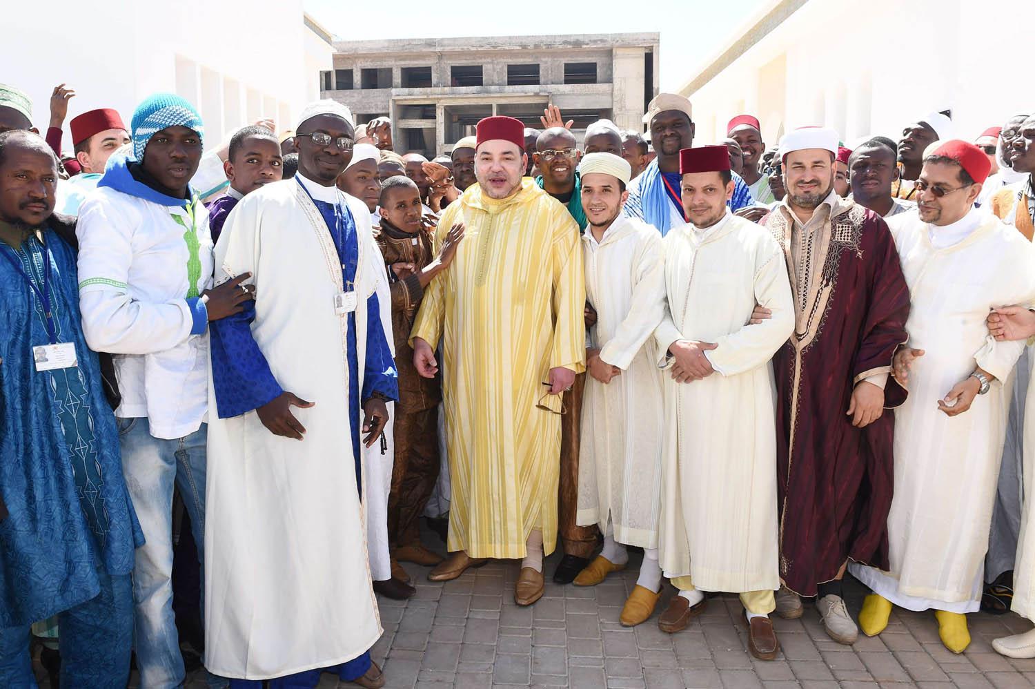 العاهل المغربي الملك محمد السادس يتوسط مواطنين في احتفال تدشين مركز تأهيل الأئمة