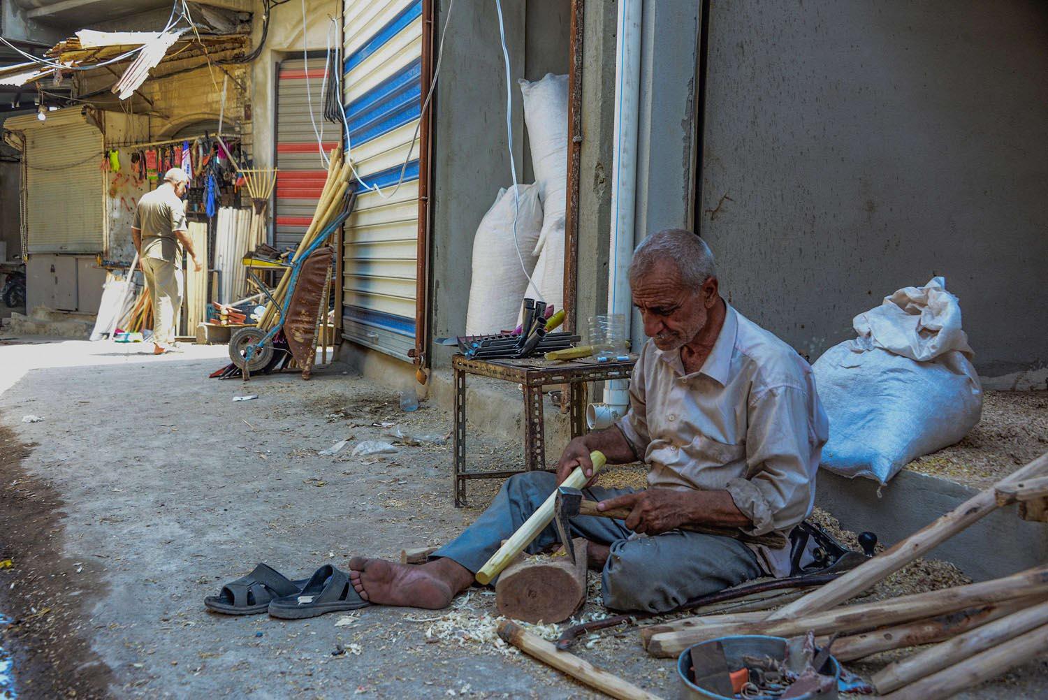 عراقي يعد معاول للبناء في سوق الموصل