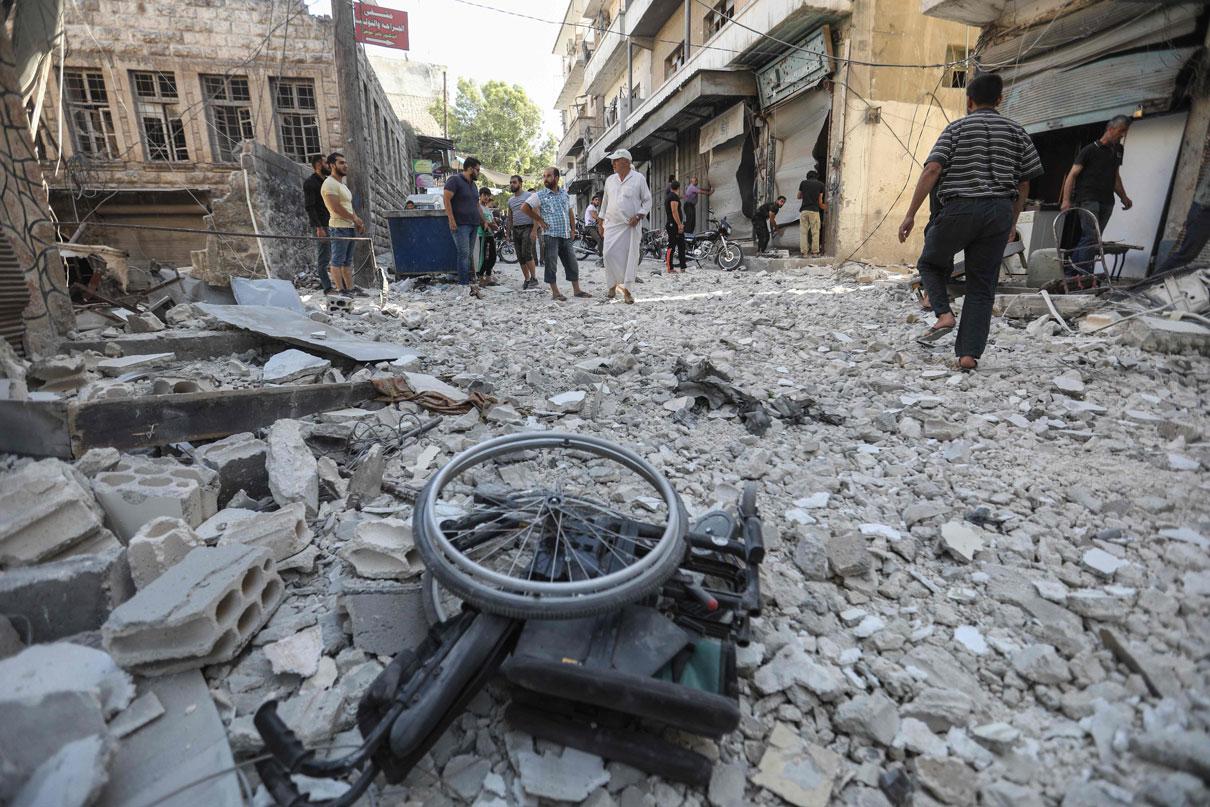 A wheelchair is seen amid the rubble of destroyed buildings following a reported regime air strike on the town of Ariha