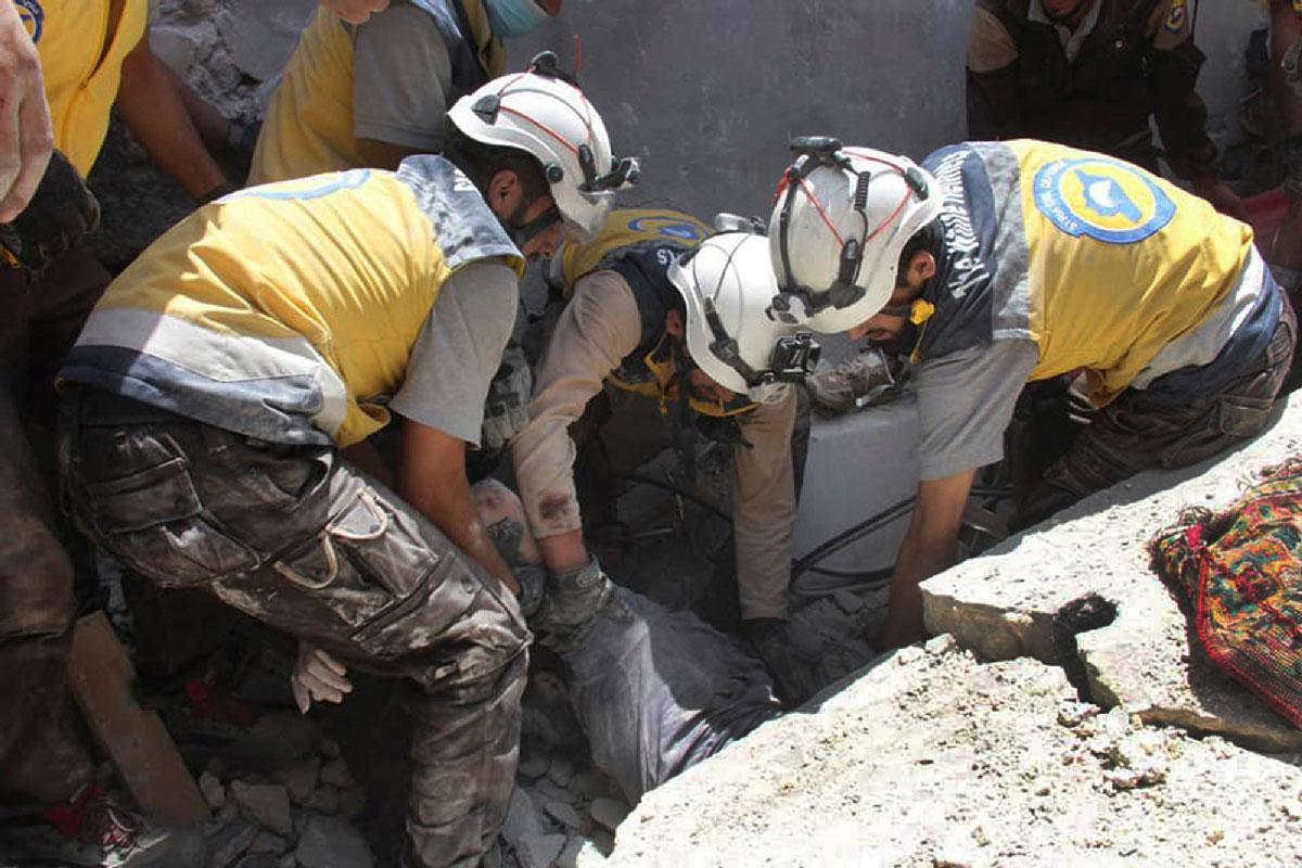 Syrian civil defense workers pull out a victim from under the rubble of a destroyed building