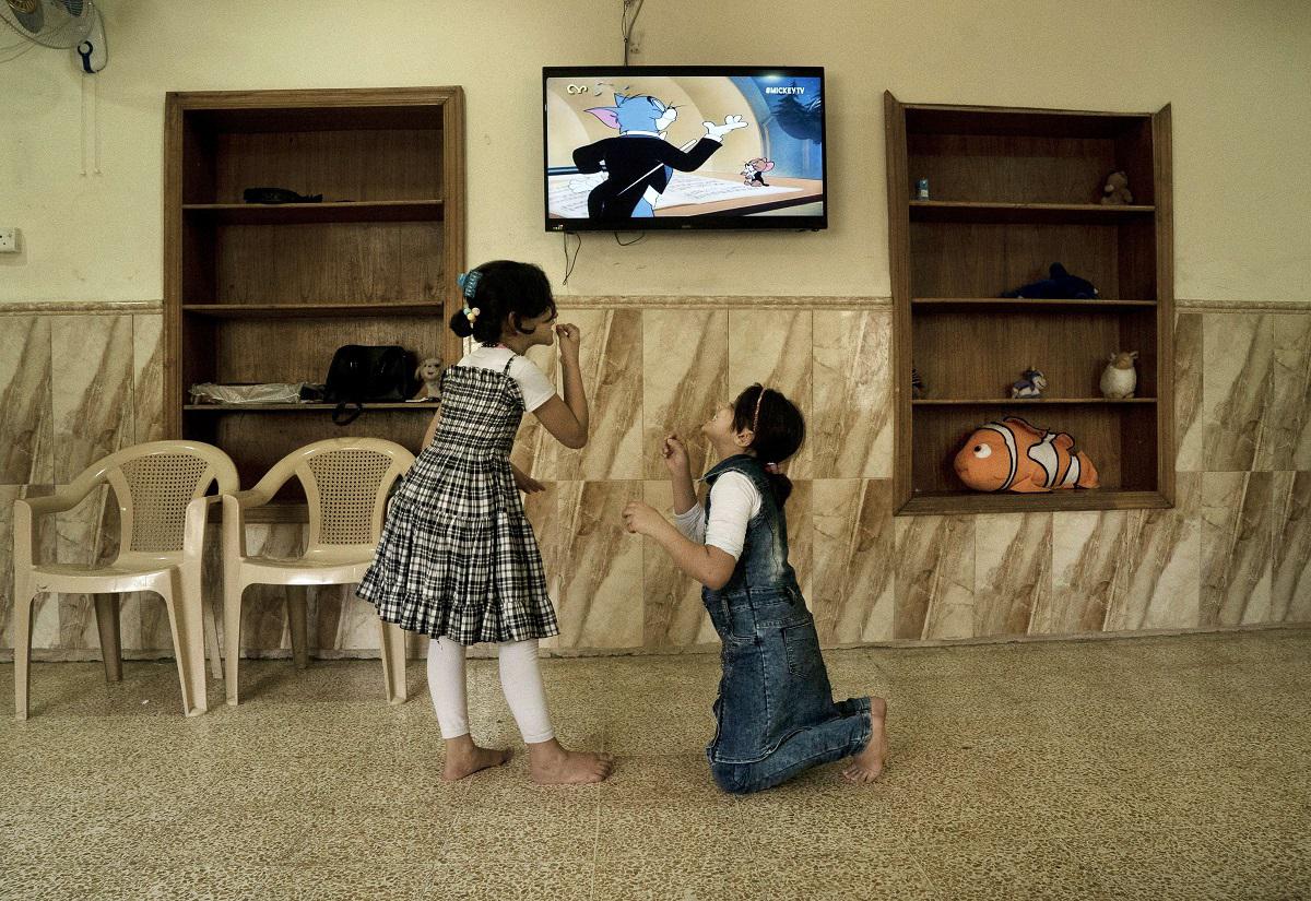 طفلتان عراقيتان في الموصل تشاهدان حلقة من توم وجيري وتقلدان حركاتهما 