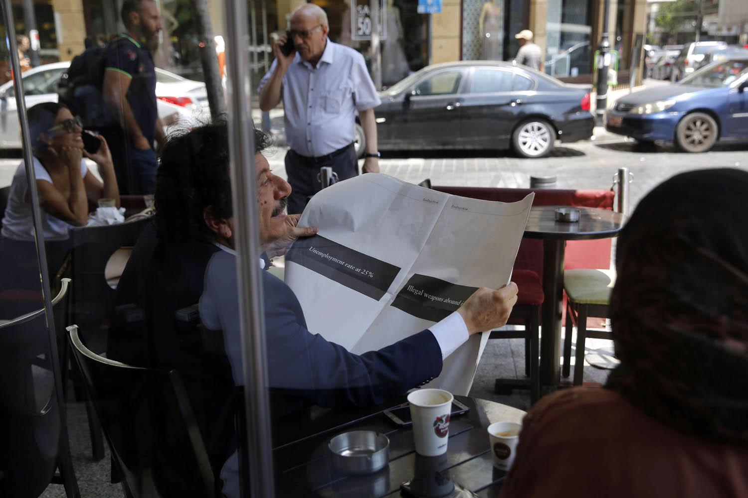 لبناني يتصفح جريدة ديلي ستار في مقهى في بيروت
