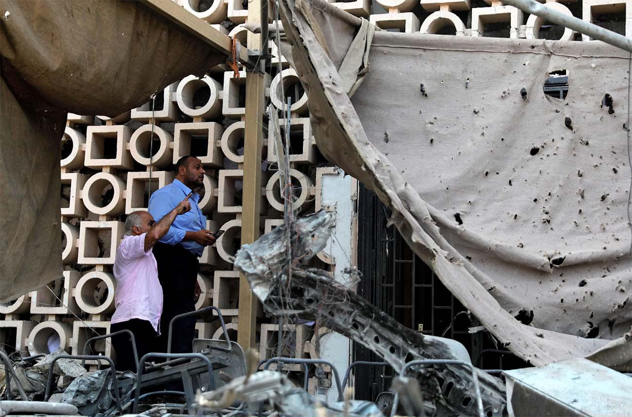 Egyptian investigators are seen in front of the damaged facade of the National Cancer Institute after the fire from last weekend's blast
