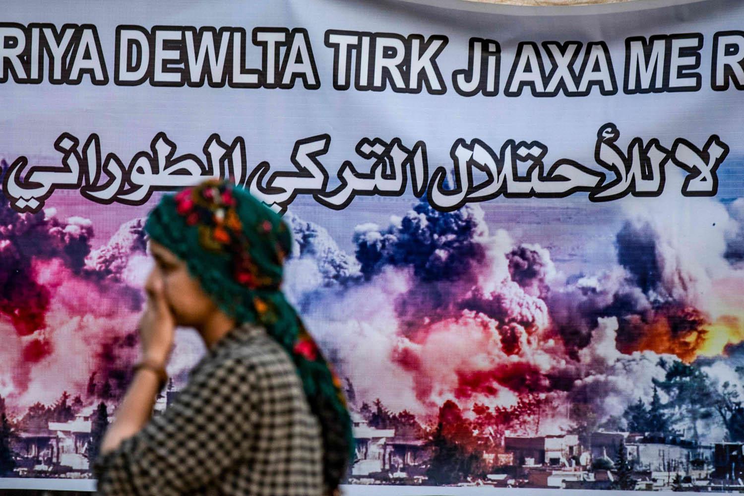 كردية تمر بالقرب من لافتة تندد بالتدخل التركية في شمال سوريا