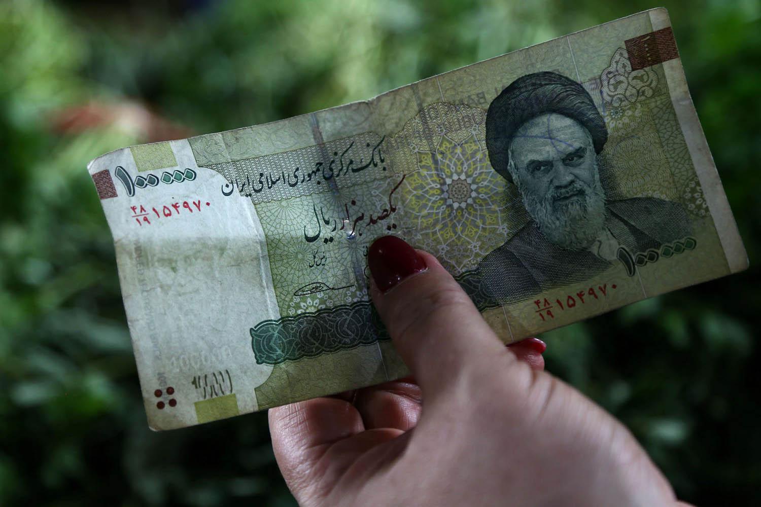 سيدة تحمل العملة الإيرانية