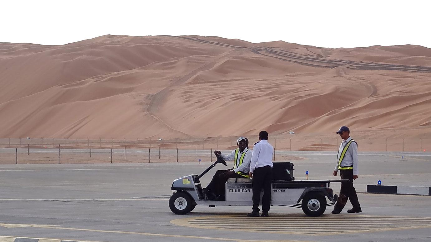 Aramco staff members stand on the tarmac at the Saudi Aramco airport
