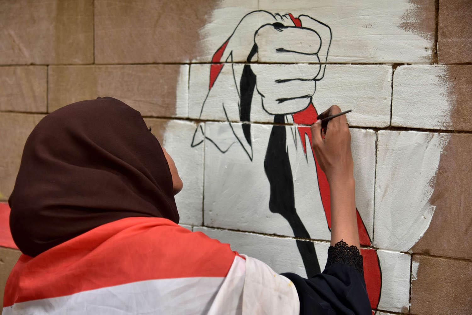 سودانية ترسم غرافيتي على جدار في الخرطوم