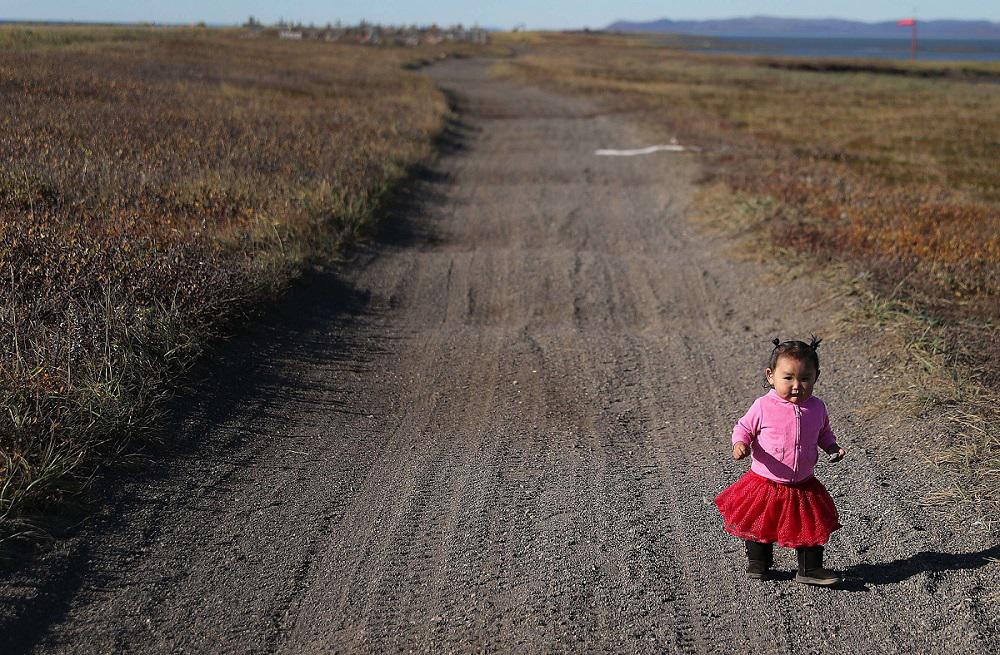 طفلة تمشي في طريق زراعي في ألاسكا حيث المنطقة مهددة بارتفاع منسوب المياه