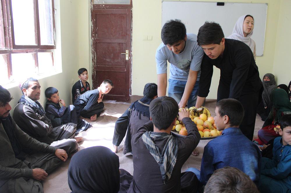 Habib (standing, left) serves fruit to parents at the Borderfree Street Kids School