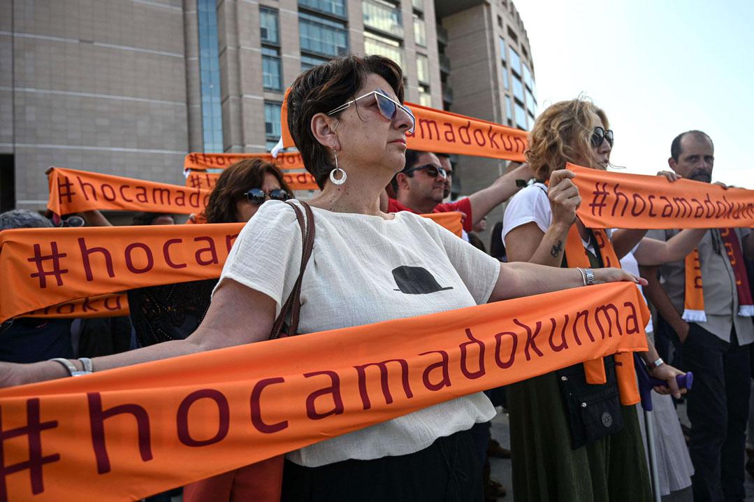 People hold scarf banners reading " Do not touch my teacher " during a demonstration outside of Istanbul's courthouse