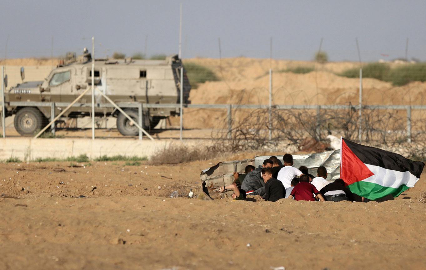 Palestinian protesters take cover during protests near the Gaza fence
