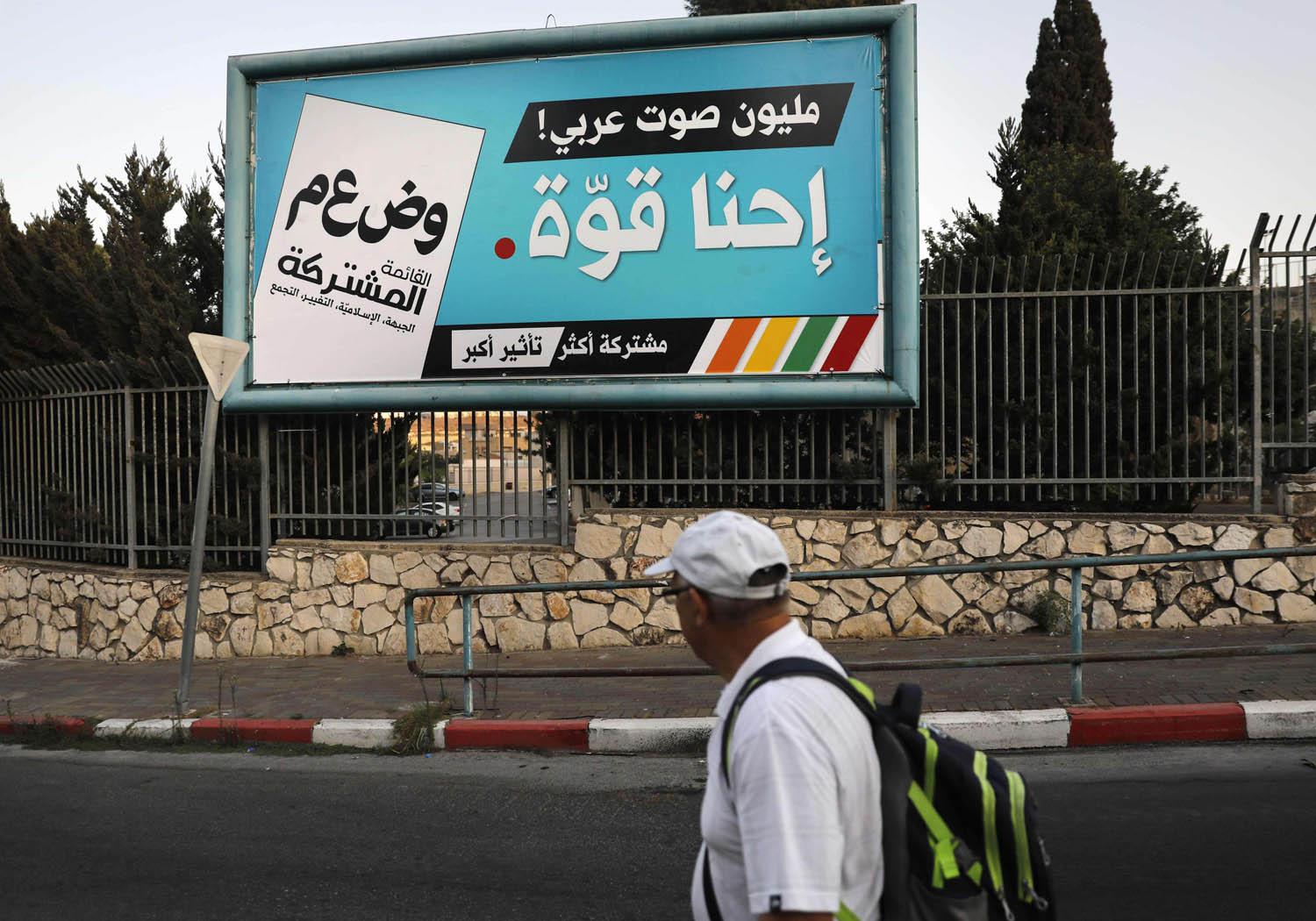 فلسطيني يمر بجانب اعلان للتصويت في الانتخابات الاسرائيلية