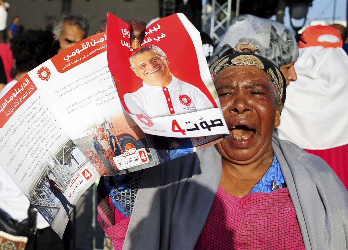 A supporter of jailed Tunisian presidential candidate Nabil Karoui shows his portrait during a gathering in Tunis