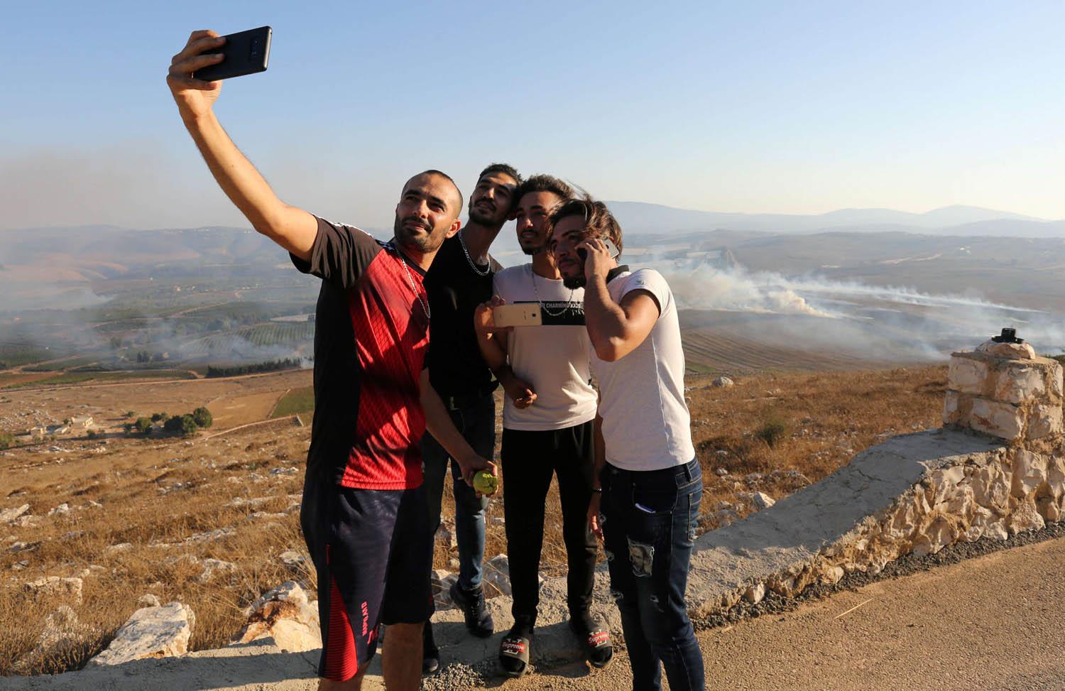 لبنانيون يأخذون صورا سيلفي مع حرائق اشعلها القصف الإسرائيلي لجنوب لبنان