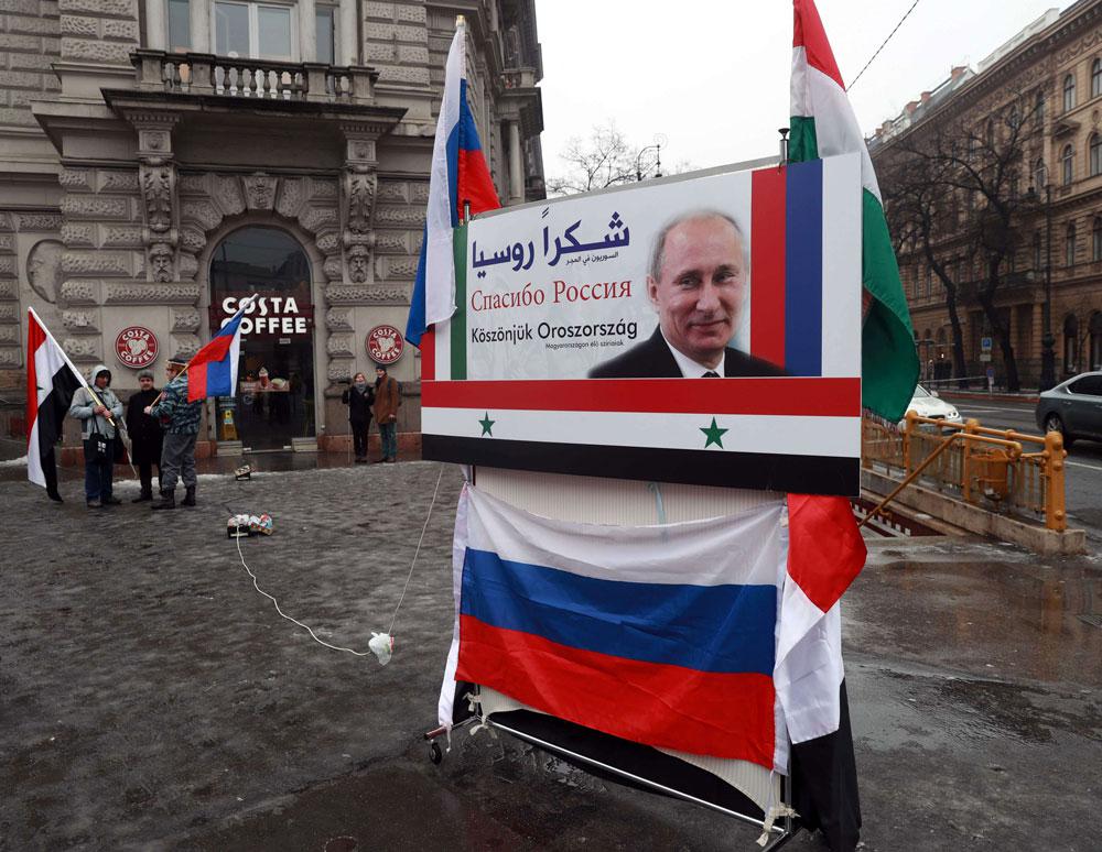 Syrians in Hungary demonstrate next to a poster depicting Russian President Valdimir Putin and reading "Thanks Russia" in downtown Budapest
