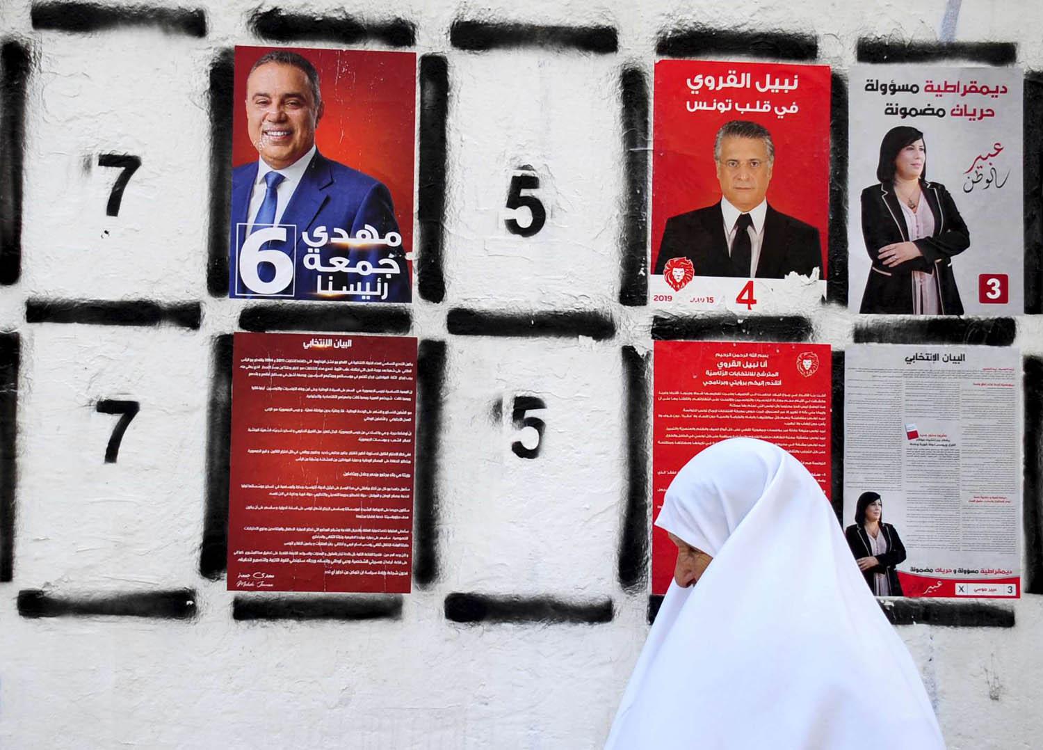 تونسية تمر من مجموعة صور وملصقات لمرشحي الرئاسة