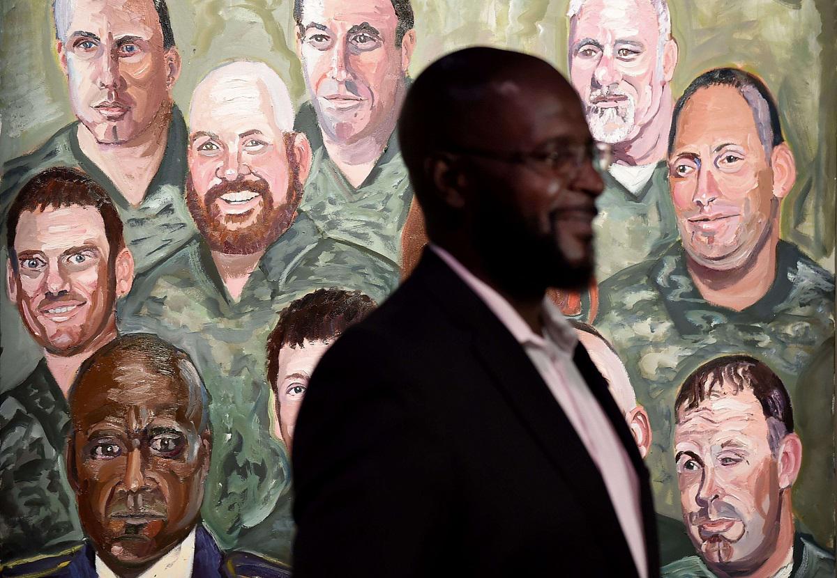 حندي أميركي شارك في حرب العراق يقف بجانب لوحة تظهر فيها صورته 