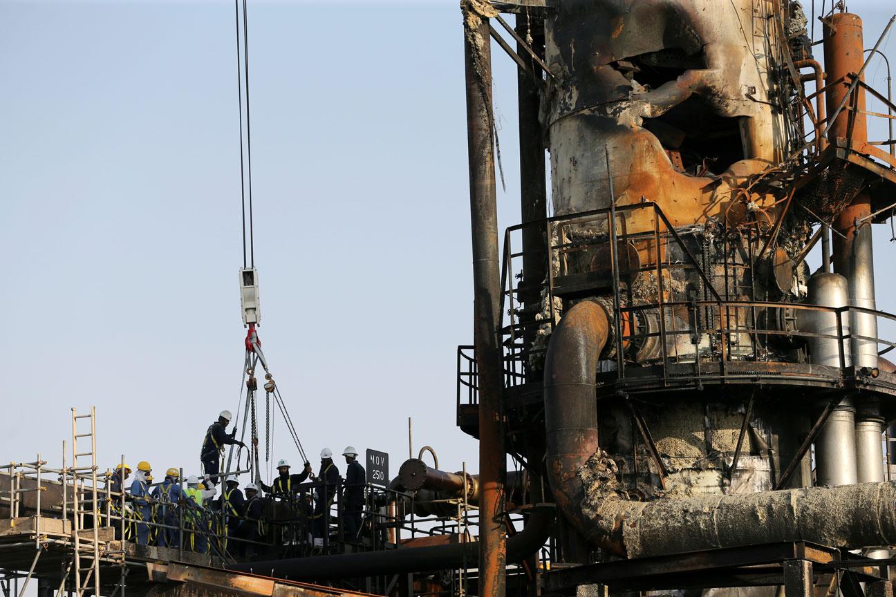 Workers are seen at the damaged site of Saudi Aramco oil facility in Abqaiq, Saudi Arabia