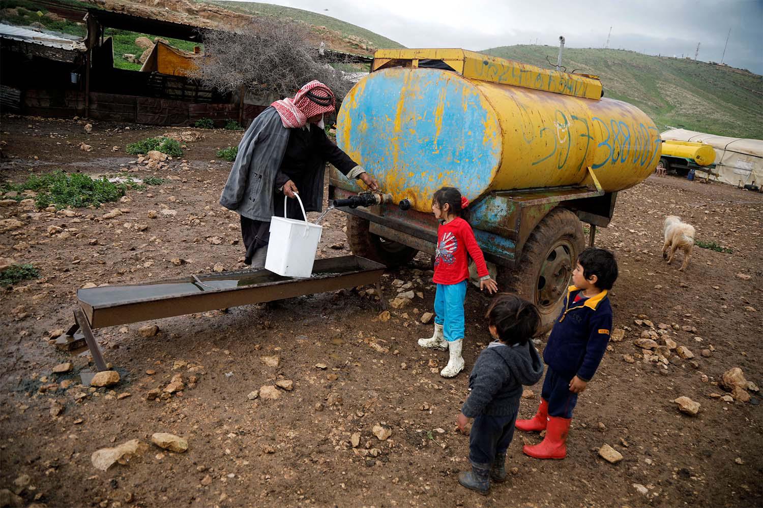 A Palestinian man fills a container with water from a tank in the Bedouin village of Al-Maleh in Jordan valley in the Israeli-occupied West Bank