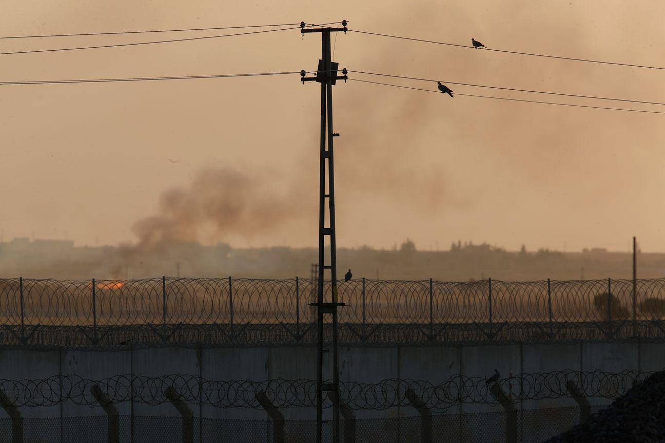 Barbed wire and smoke seen in a photo taken from the Turkish side of the border between Turkey and Syria