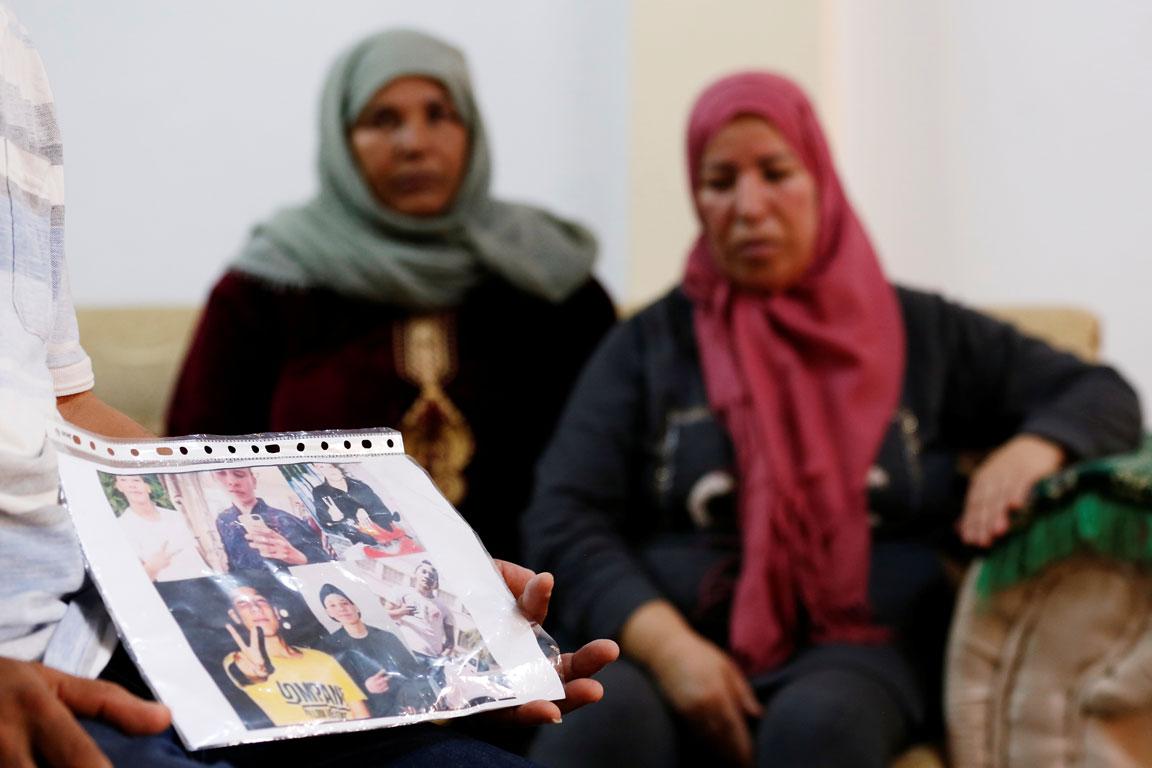 Mokhtar Hmidi, the father of Fakher who still unaccounted for after last week's capsizing off the Italian island of Lampedusa, shows pictures of his son, with Fakher's mother pictured in the background