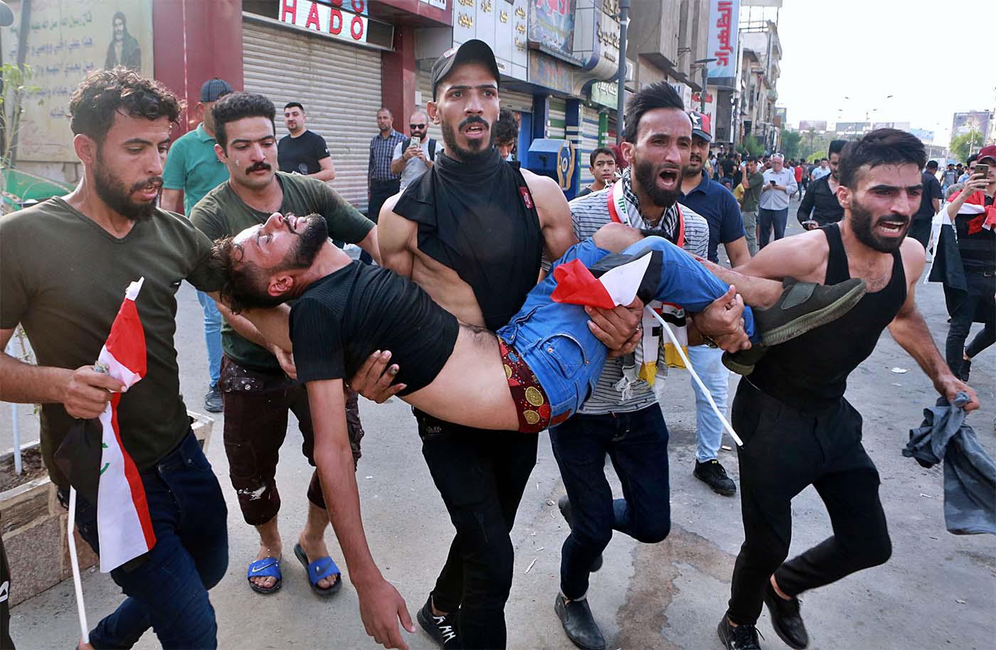 An injured protester is carried after reacting to tear gas fired by security forces during a protest in Tahrir Square