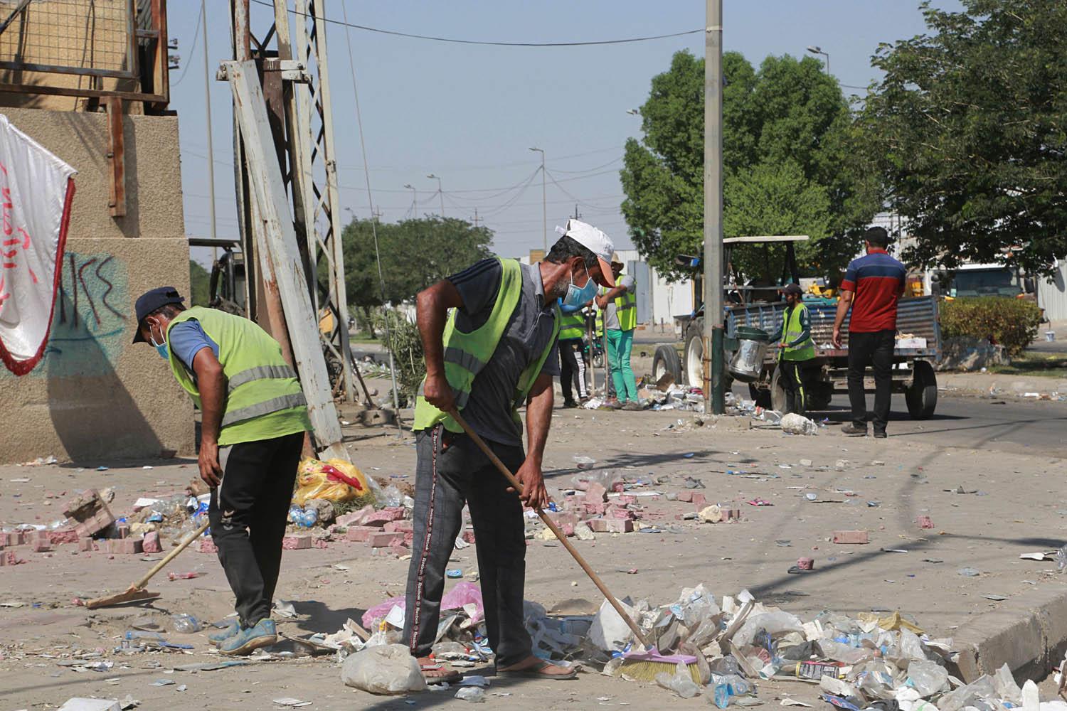 عمال بلدية يرفعون انقاضا بعد تظاهرة في بغداد