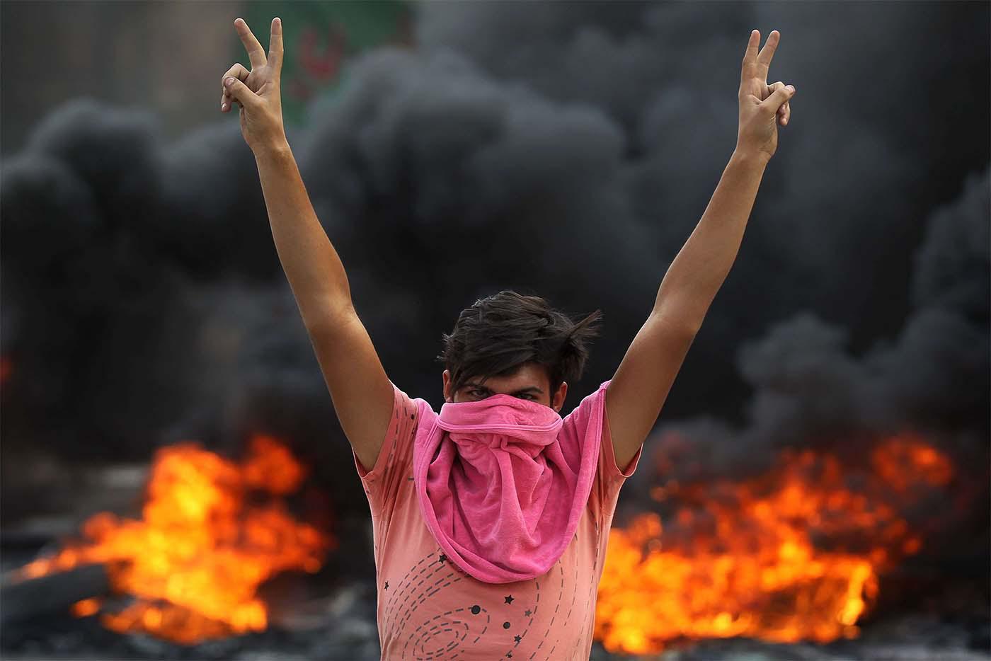 An Iraqi protester flashes the v-sign during a demonstration against state corruption, failing public services and unemployment in Baghdad