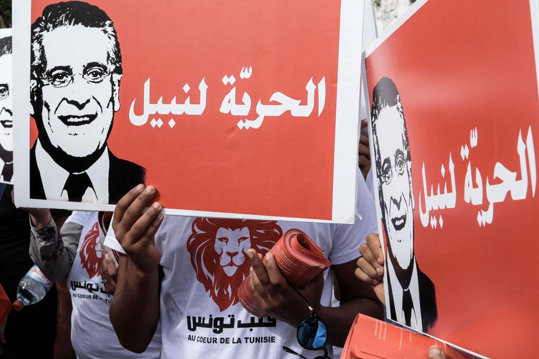 Supporters of the jailed Tunisian media magnate and presidential candidate Nabil Karoui hold placards