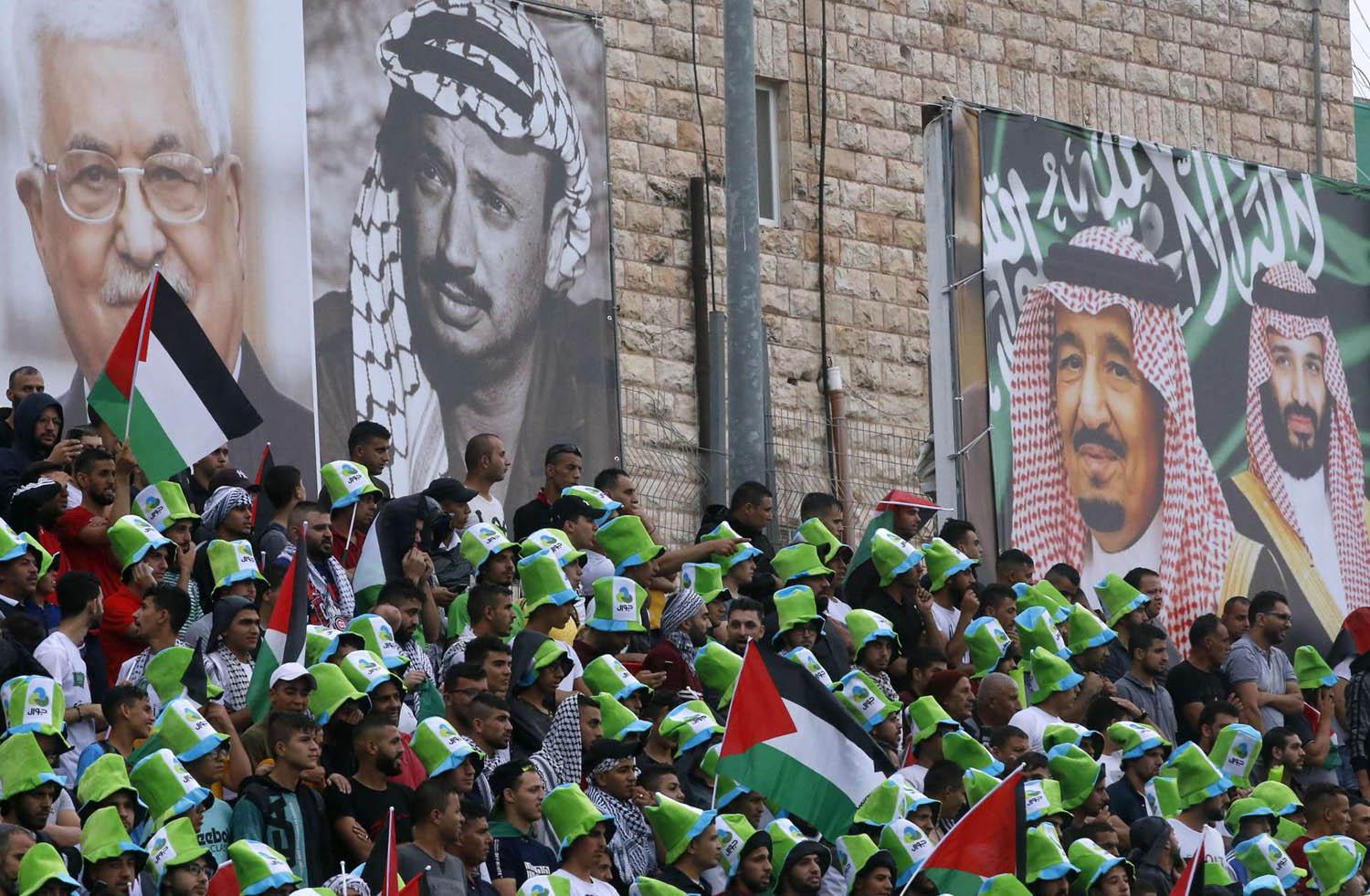 فلسطينيون يحضرون مباراة بين الفريق السعودي والفريق الفلسطيني في الرم في الضفة الغربية