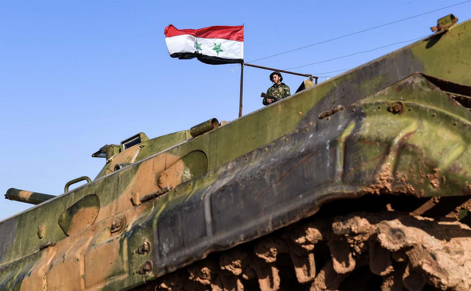 A Syrian soldier stands in a government forces' position near a deployed infantry-fighting vehicle