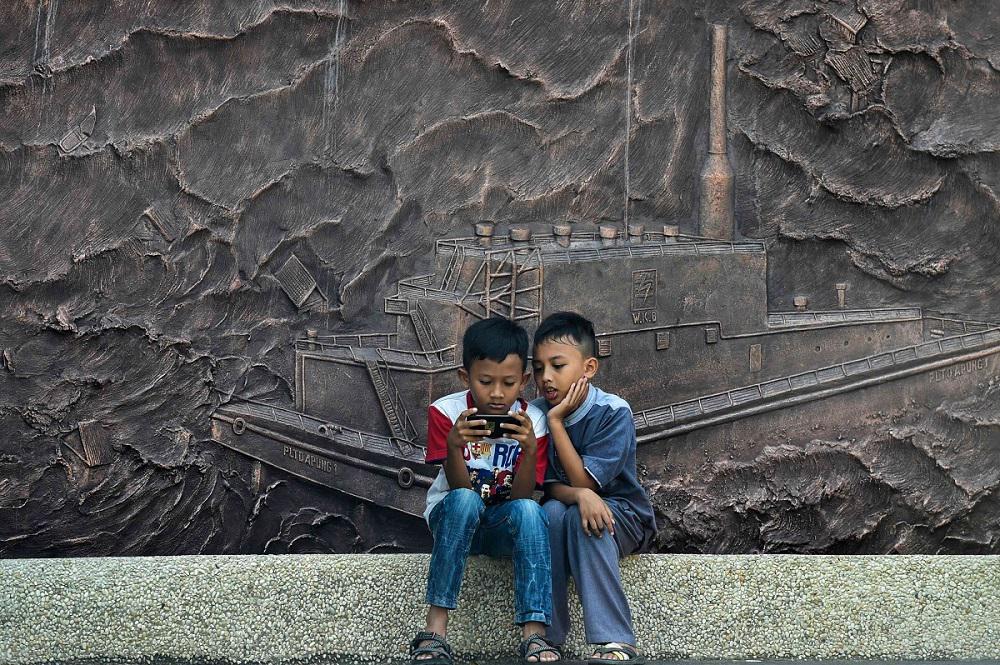طفلان اندونيسيان يستخدمان هاتفا محمولا