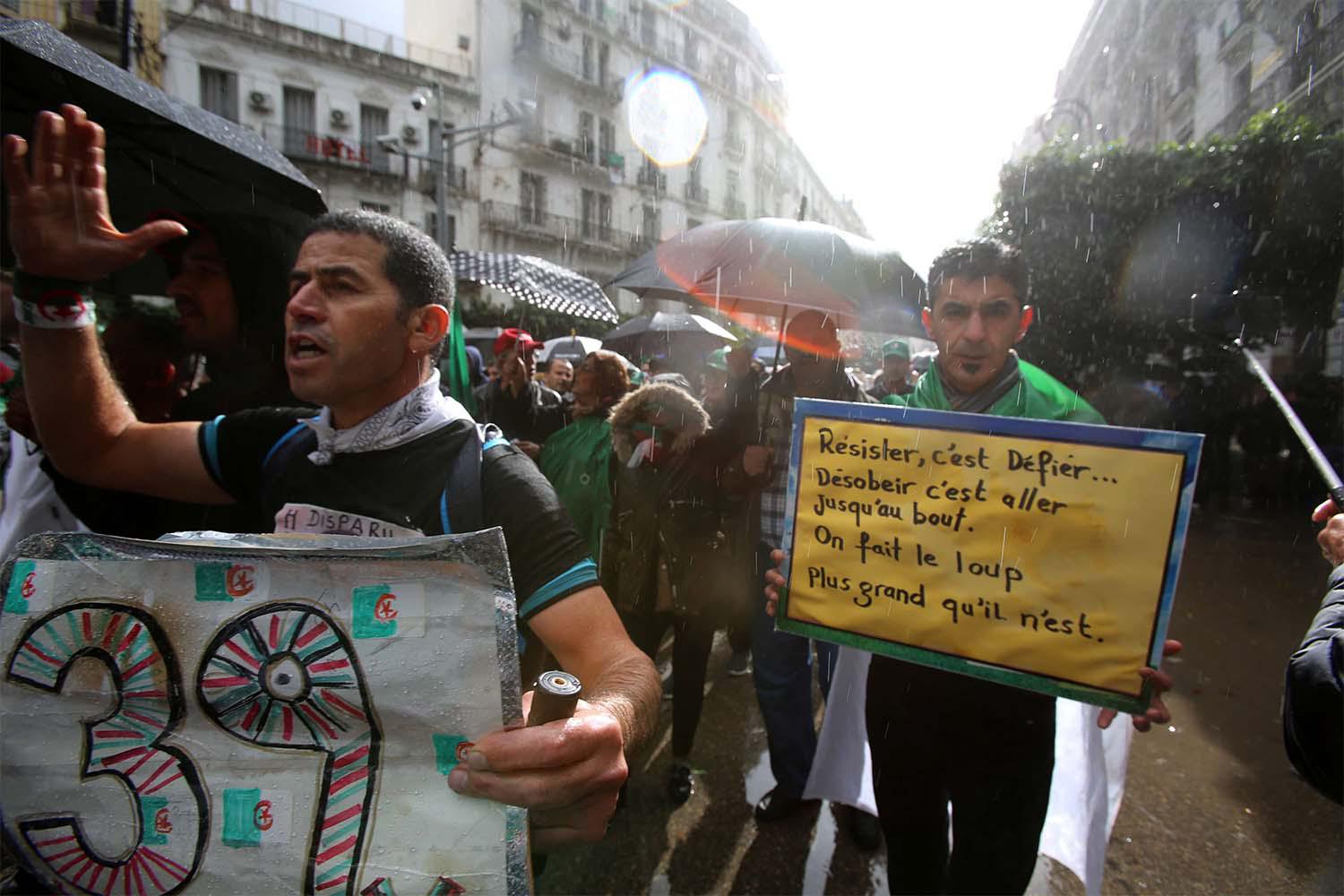 Demonstrators march under heavy rain during a protest against the country's ruling elite