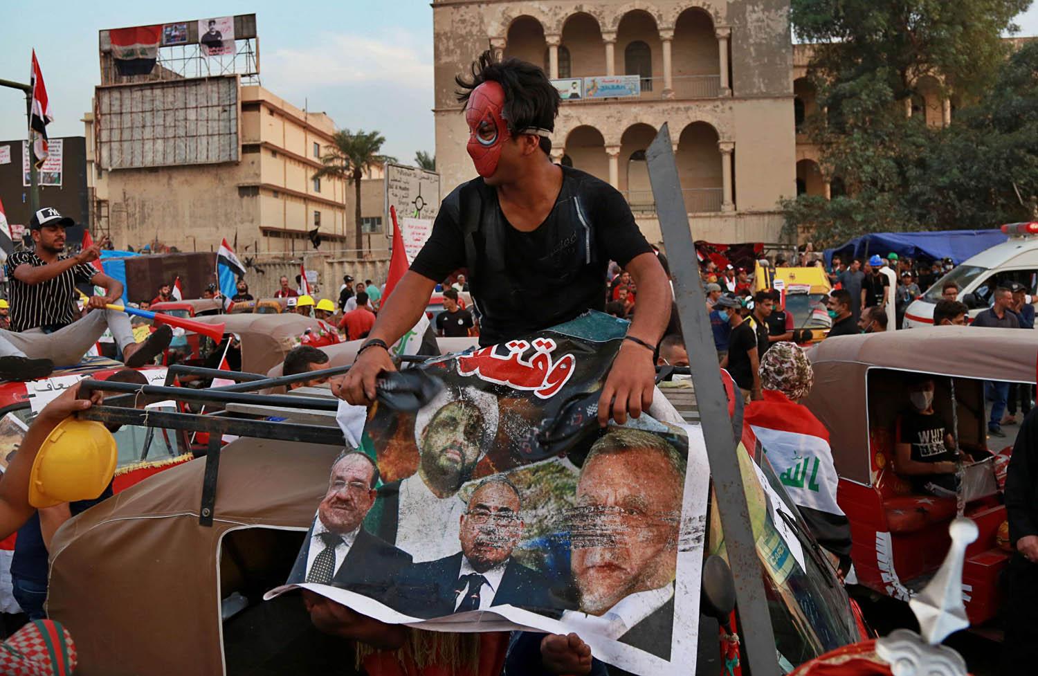 عراقي يضع صورة لسياسيين عراقيين محسوبين على إيران
