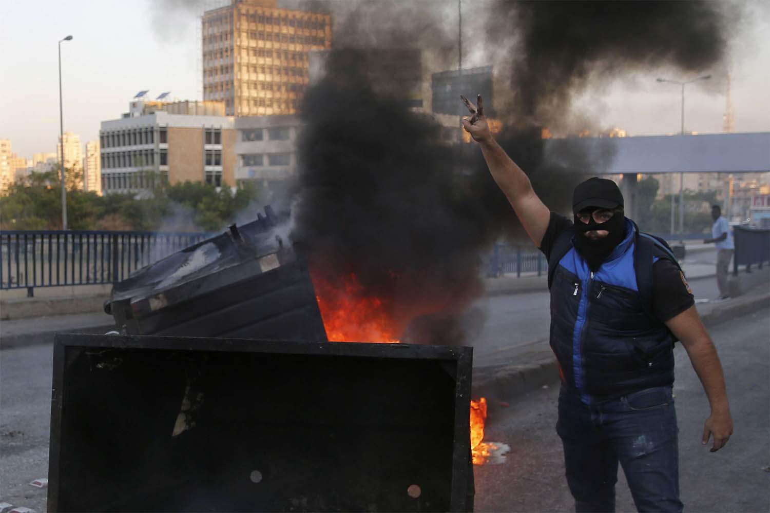Anti-government protesters block a main highway by garbage containers in Beirut
