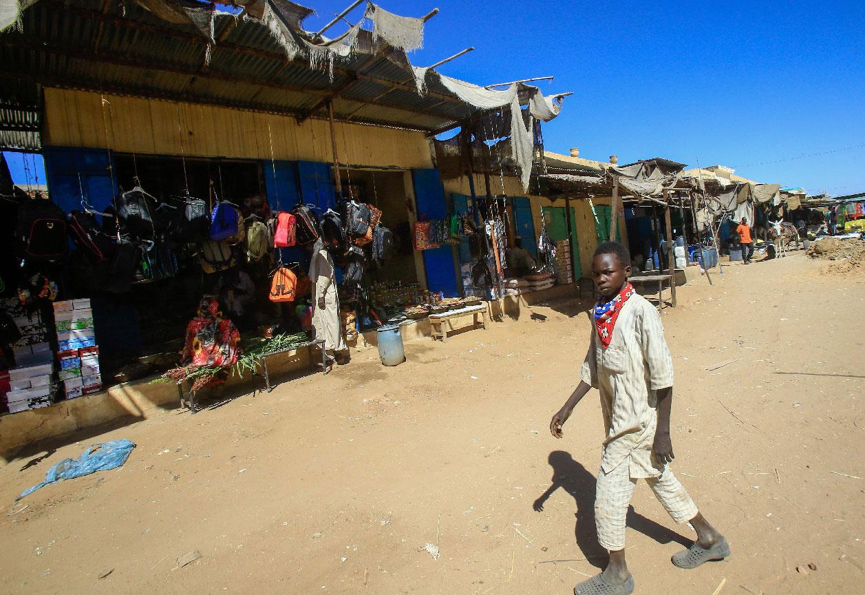 A diplaced Sudanese boy walks through the market of the Abu Shouk camp for internally displaced persons