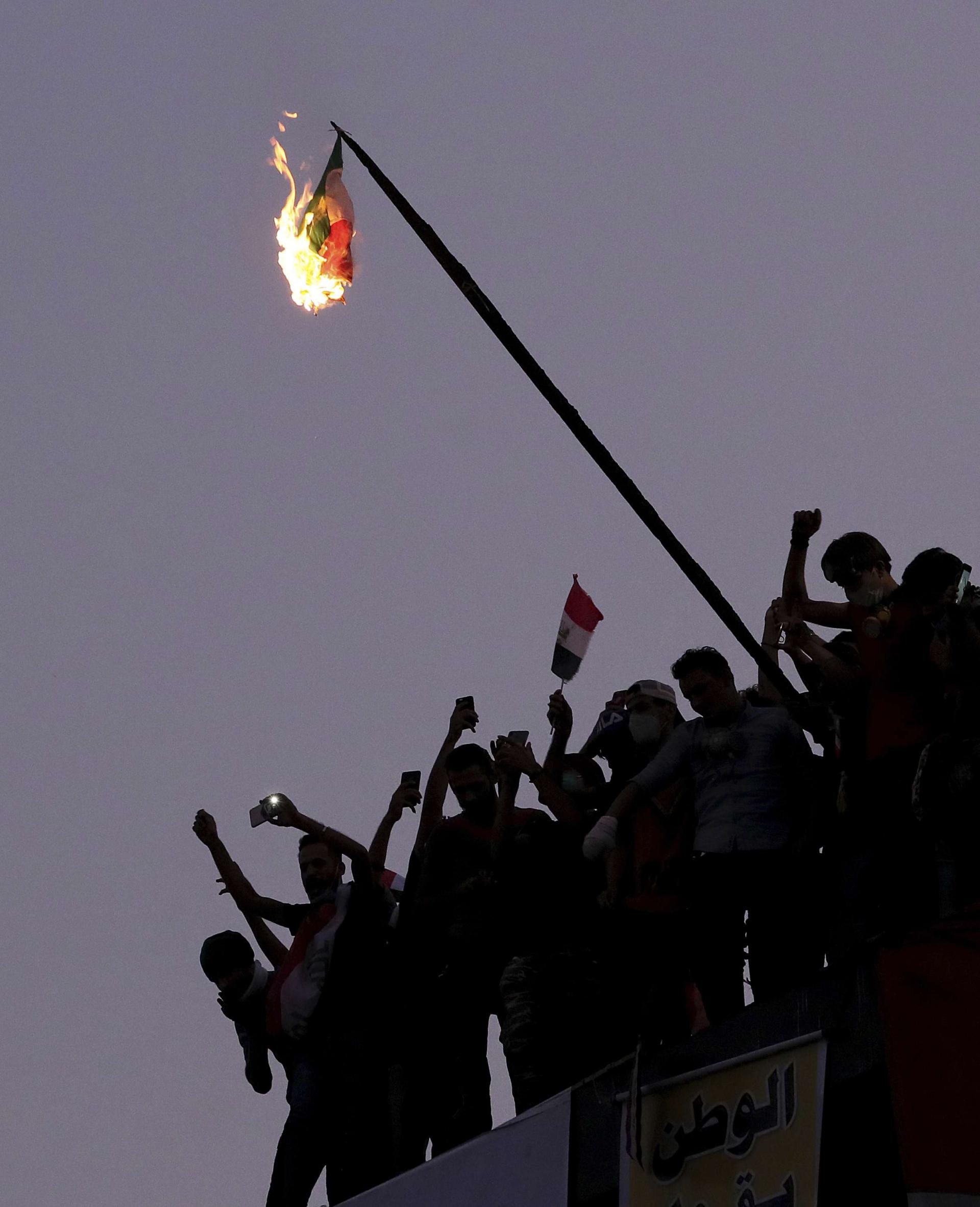 Iraqi anti-government protesters burn the Iranian flag during a demonstration in Baghdad