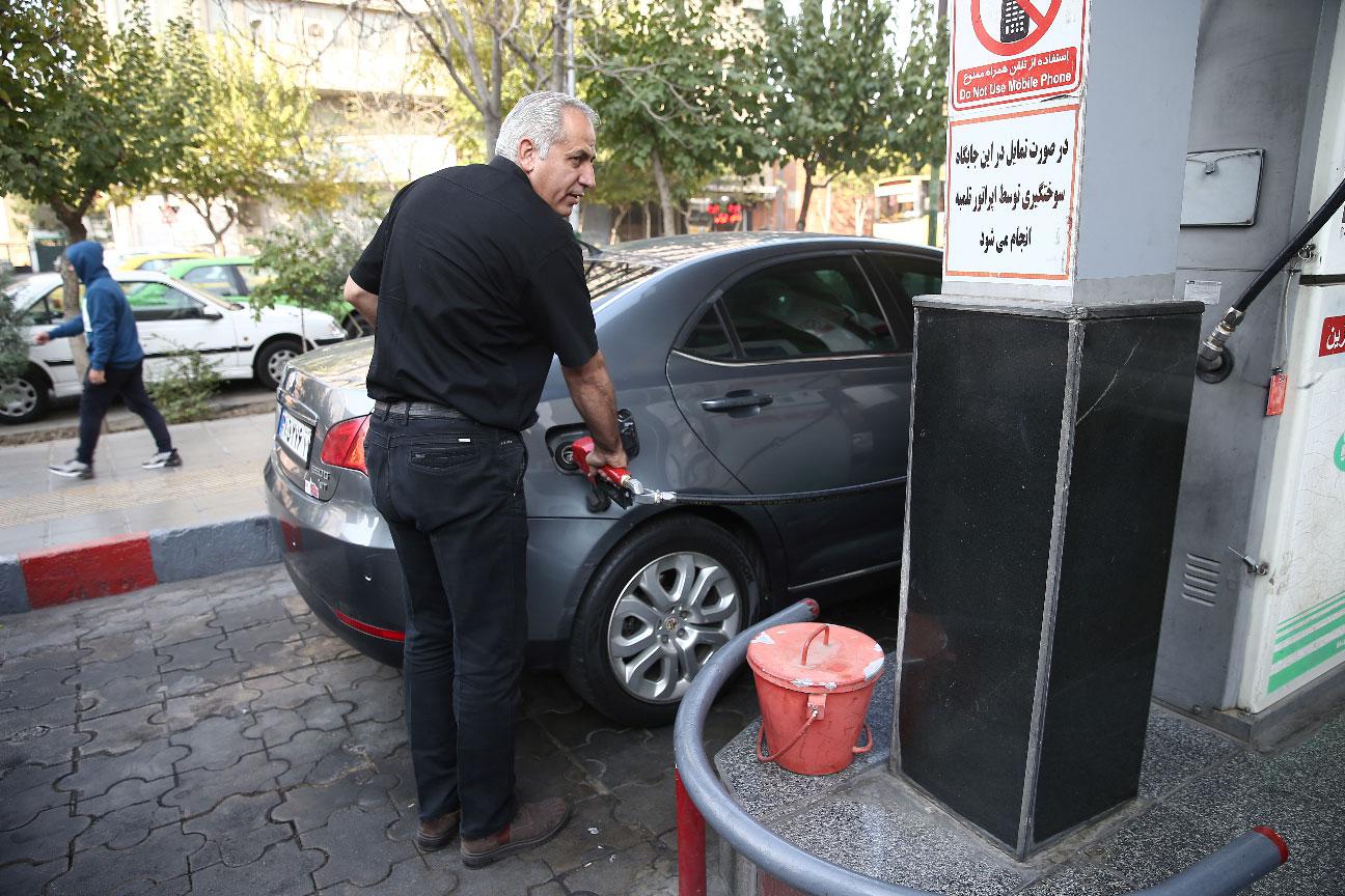 A man fills up his car's tank at a petrol station, after fuel price increased, in Tehran